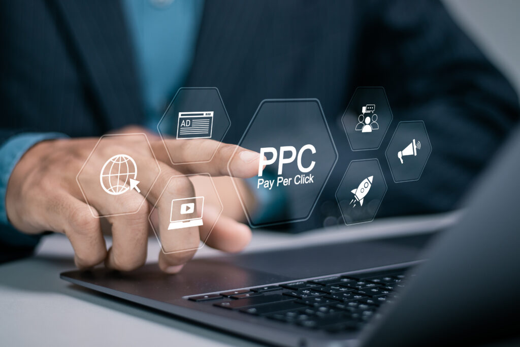 Businessman using laptop with PPC icon on virtual screen.