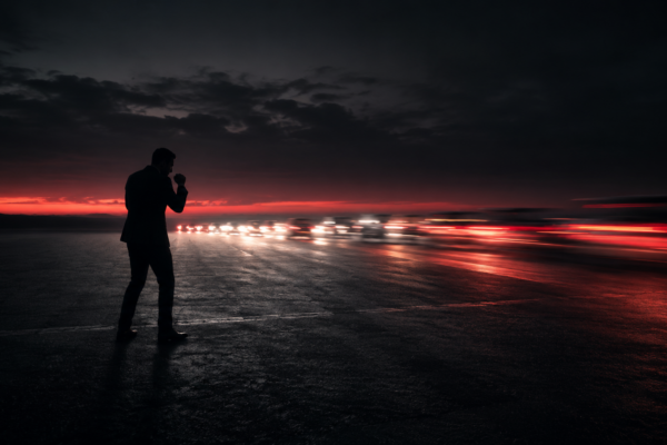 Dealership manager in a defensive stance as competitor taillights speed past, symbolizing reactive versus proactive marketing